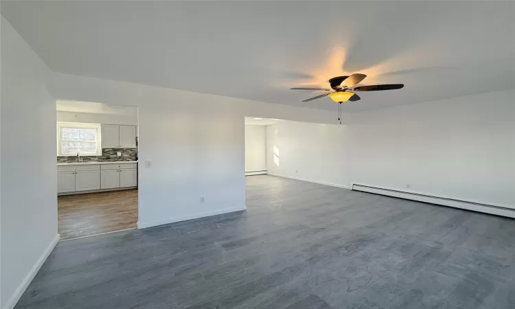 Empty room featuring hardwood / wood-style flooring, baseboard heating, and ceiling fan