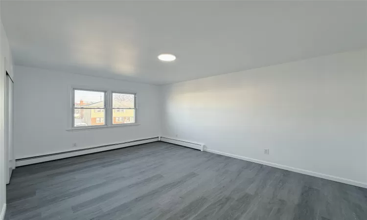 Empty room featuring a baseboard radiator and hardwood / wood-style flooring