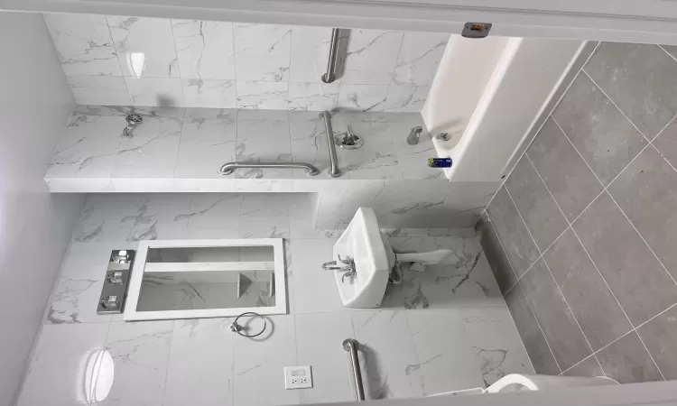 Bathroom featuring tile patterned floors, tile walls, and tiled shower / bath