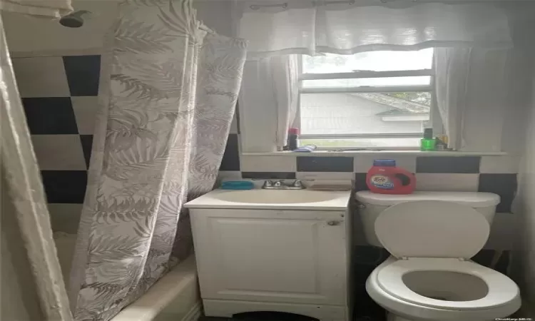 Full bathroom with shower / bath combo with shower curtain, vanity, and toilet