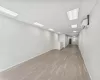 Basement with a paneled ceiling, light wood-type flooring, and an AC wall unit