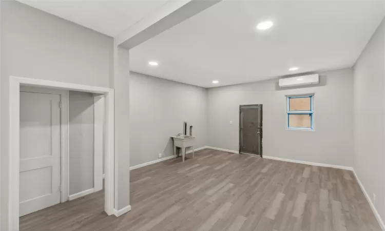 Clothes washing area with light hardwood / wood-style flooring and a wall unit AC