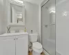 Bathroom with vanity, toilet, and a shower with door