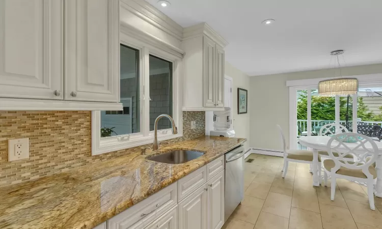 Kitchen with backsplash, white cabinets, and sink