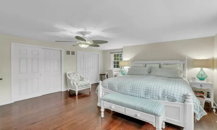 Bedroom with multiple closets, ceiling fan, and dark hardwood / wood-style floors