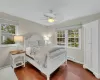 Bedroom with ceiling fan, a baseboard heating unit, dark wood-type flooring, and multiple windows