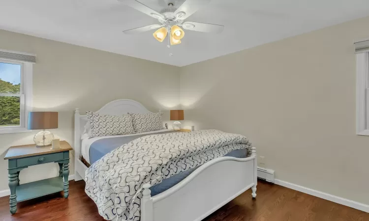 Bedroom featuring ceiling fan, dark wood-type flooring, and a baseboard radiator