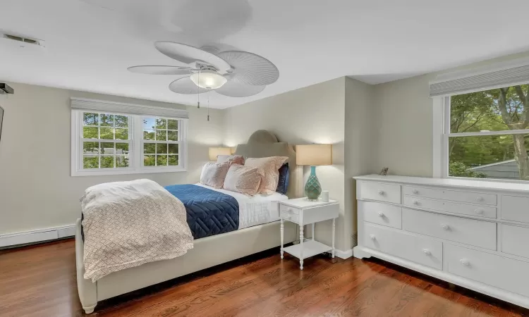 Bedroom with baseboard heating, ceiling fan, and dark wood-type flooring