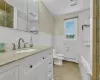 Full bathroom with tile patterned flooring, tile walls, and a baseboard heating unit