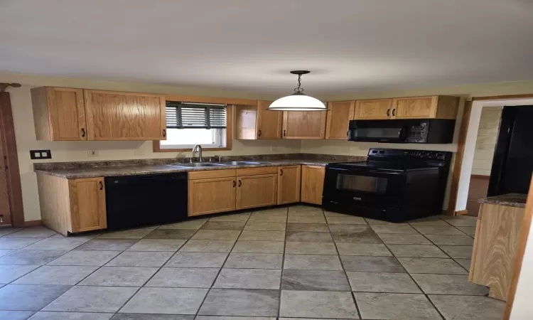 Kitchen featuring pendant lighting, sink, light tile patterned floors, and black appliances