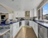 Kitchen with white cabinetry, decorative light fixtures, wall chimney range hood, and appliances with stainless steel finishes