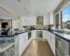 Kitchen with white cabinets, wall chimney exhaust hood, decorative light fixtures, and appliances with stainless steel finishes