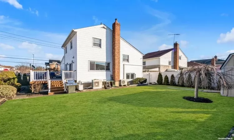 Rear view of property with a lawn, ac unit, and a deck