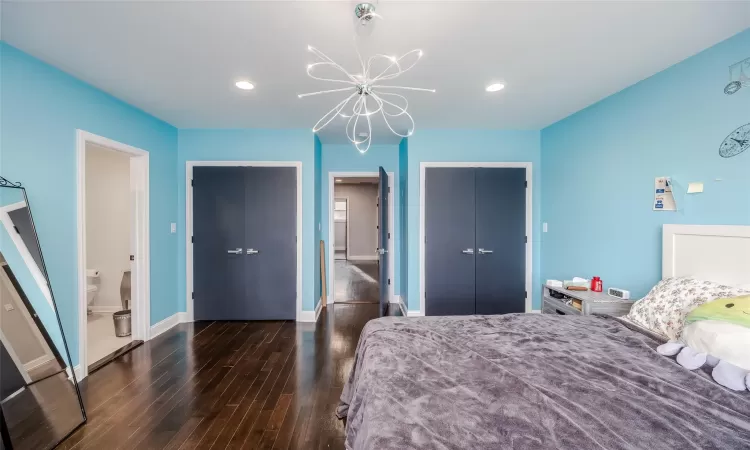 Bedroom featuring ensuite bathroom, a closet, dark hardwood / wood-style floors, and an inviting chandelier