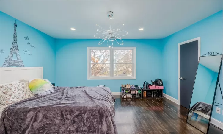 Bedroom with dark wood-type flooring and an inviting chandelier