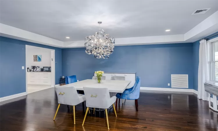 Dining room featuring a raised ceiling, dark hardwood / wood-style floors, and an inviting chandelier