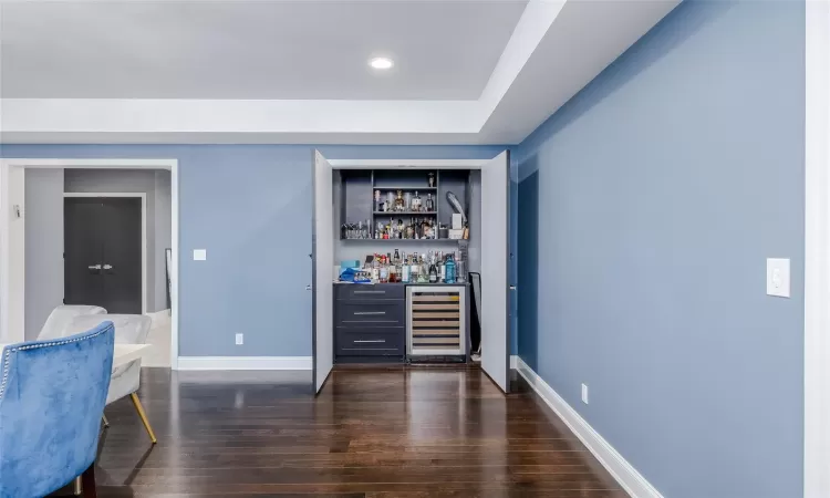 Bar with wine cooler and dark hardwood / wood-style flooring