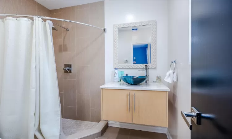 Bathroom featuring tile patterned flooring, vanity, and walk in shower