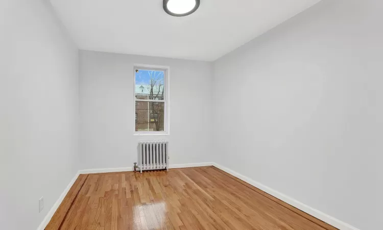 Spare room featuring hardwood / wood-style flooring and radiator heating unit