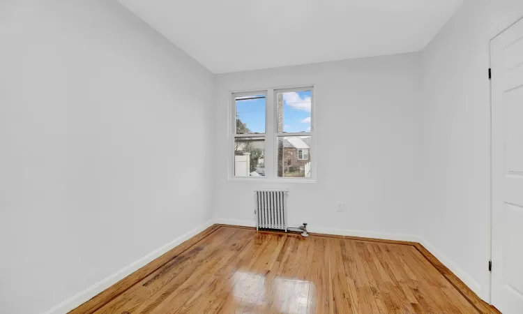 Spare room with radiator heating unit and wood-type flooring