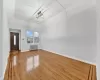 Unfurnished living room featuring wood-type flooring, radiator, and an inviting chandelier