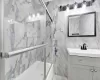 Bathroom with vanity, tile walls, and bath / shower combo with glass door