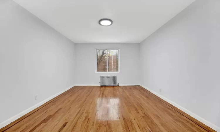 Unfurnished room with light wood-type flooring and radiator heating unit