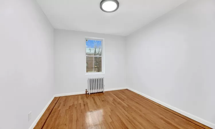 Unfurnished room featuring hardwood / wood-style floors and radiator