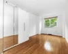 Unfurnished bedroom with wood-type flooring, radiator, and a closet