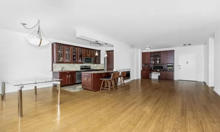 Kitchen featuring light wood-type flooring, appliances with stainless steel finishes, a center island, and a kitchen breakfast bar