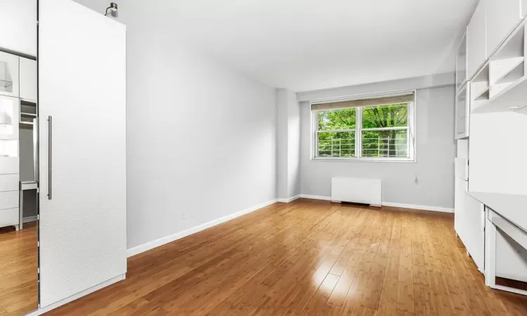 Unfurnished living room with radiator heating unit and light wood-type flooring