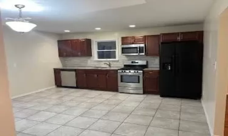 Kitchen with backsplash, sink, light tile patterned floors, and stainless steel appliances