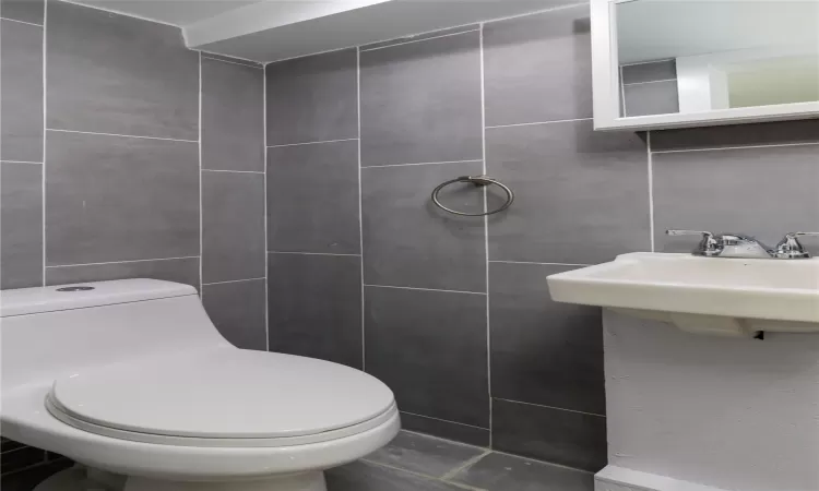 Bathroom featuring toilet and tile walls