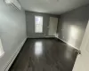 Spare room with dark wood-type flooring, a wall unit AC, and a baseboard radiator