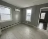 Empty room featuring a wall mounted air conditioner, light hardwood / wood-style floors, and baseboard heating