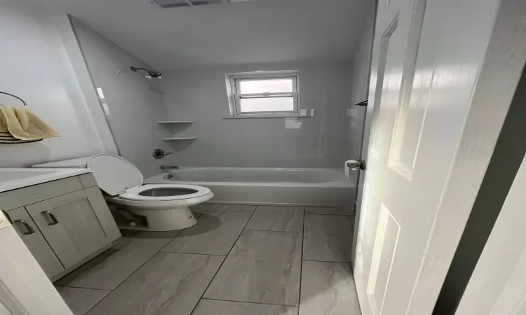 Full bathroom featuring vanity, tiled shower / bath, and toilet