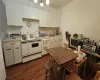 Kitchen featuring white appliances, backsplash, dark wood-type flooring, sink, and white cabinetry