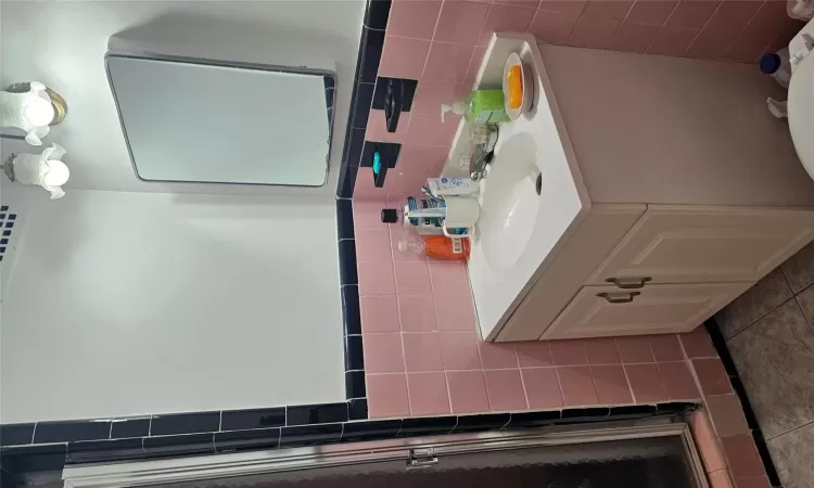 Bathroom with tile patterned floors, a shower with door, vanity, and tile walls