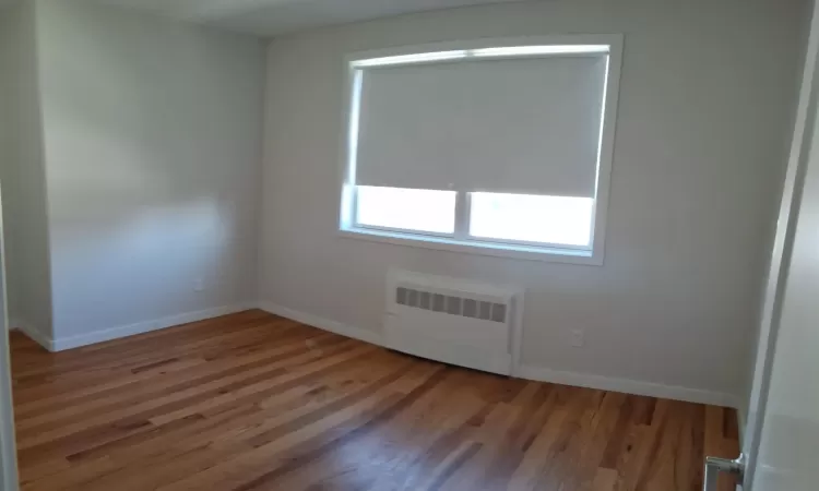 Unfurnished room featuring radiator heating unit and wood-type flooring