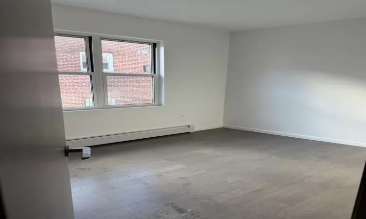 Unfurnished room featuring a baseboard radiator and hardwood / wood-style flooring