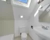 Full bathroom featuring tile patterned floors, toilet, separate shower and tub, sink, and vaulted ceiling with skylight