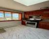 Kitchen with ventilation hood, tasteful backsplash, baseboard heating, and stainless steel gas range