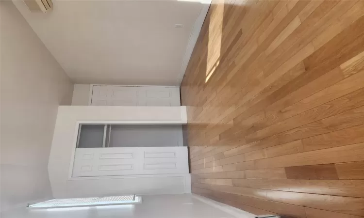 Unfurnished bedroom with a closet, light hardwood / wood-style flooring, and a wall mounted air conditioner