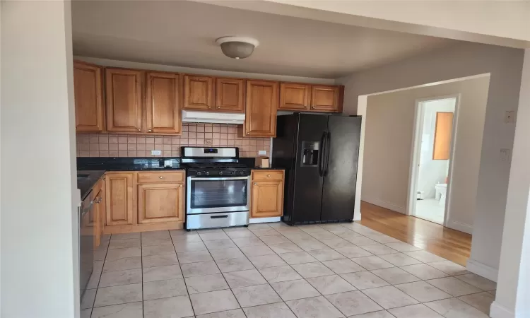 Kitchen with light tile patterned floors, backsplash, and appliances with stainless steel finishes