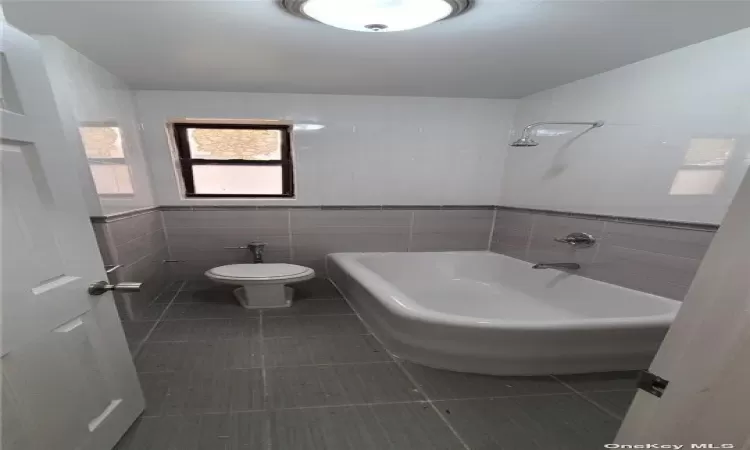 Bathroom featuring tile patterned flooring, toilet, and tile walls