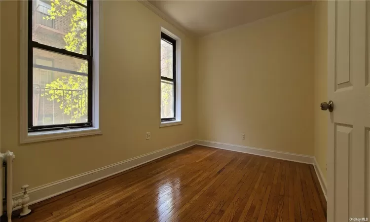 Unfurnished room featuring hardwood / wood-style floors, radiator, and crown molding