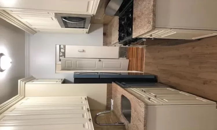 Kitchen featuring sink, dark hardwood / wood-style flooring, stove, dishwashing machine, and ornamental molding