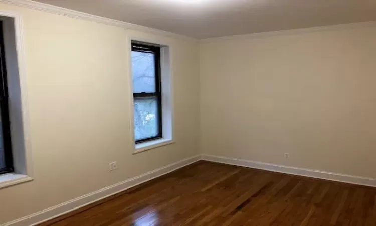 Empty room featuring dark hardwood / wood-style floors and ornamental molding