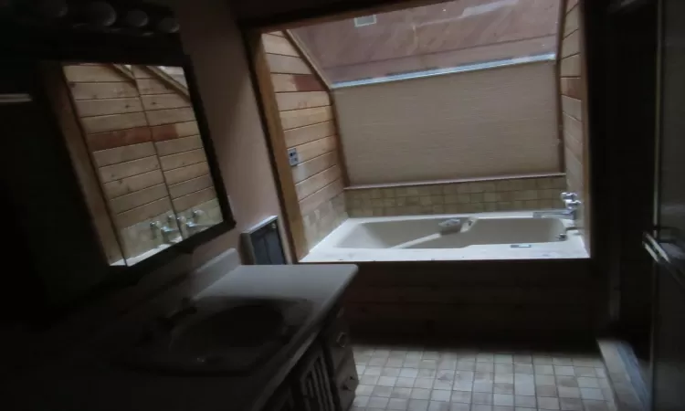 Bathroom with tile patterned flooring, vanity, and tiled tub