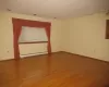 Unfurnished room featuring hardwood / wood-style flooring and a baseboard heating unit